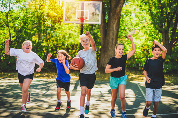 teens in sportswear playing basketball game outside together run together