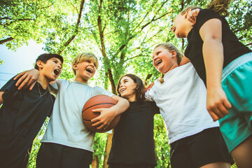 teens in sportswear playing basketball game outside together