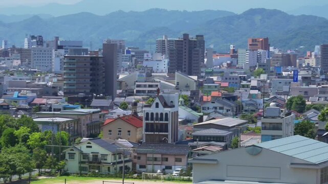 Tottori Castle (Japan's Top 100 Castle), from ancient stone walls on the mountain, blends modern city, distant mountains, blue sky and lush greenery, showing history - present integration.
