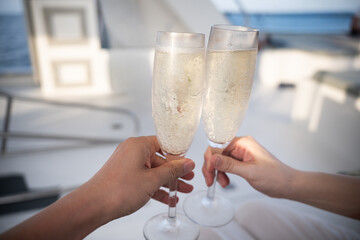 Close up of two champagne glasses making a toast on tropical resort, celebration moment
