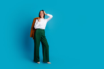 Successful woman in stylish outfit posing with elegance against blue background, showcasing modern and professional fashion