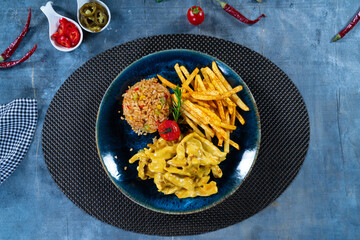 Curry Chicken with Bulgur Pilaf and French Fries on Blue Plate