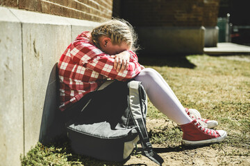 sad girl Bullying in Schoolyard sit on the ground