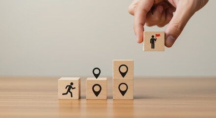 A wooden table with small wooden cubes stacked like stairs, each cube showing simple line icons symbolizing progress.