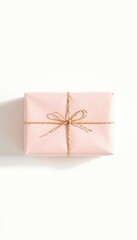 A softly wrapped gift in delicate pink paper, tied with rustic twine, against a bright, clean, minimalist background