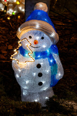 winter Christmas decorations with glowing in the dark cute led snowman and festive garlands 