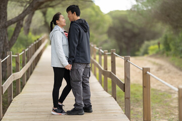 Loving couple holding hands gazing on wooden boardwalk
