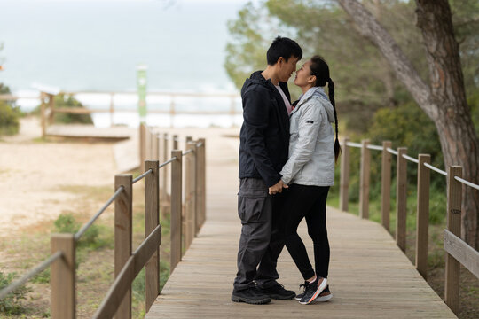 Young couple holding hands on a wooden boardwalk near the beach