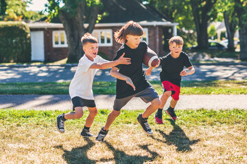 brother playing American football. Kids play football in sunny summer park.