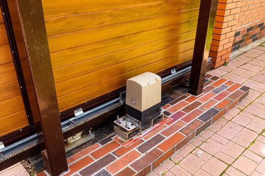 A low angle shot features a wooden gate and a motor mechanism set on a brick surface