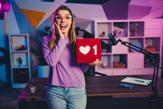 Happy young female blogger delighted while sharing content in a creative workspace with neon lights