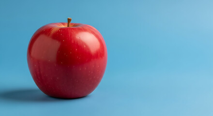 A single, vibrant red apple sits against a smooth, light-blue background.