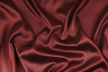 Crumpled, wrinkled maroon colored glossy silk satin texture. Shiny smooth fabric with soft folds, cloth with wave drapery. Elegant and rich background, wallpaper, backdrop. Flat lay, top view