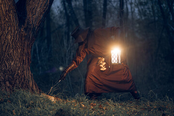 Mysterious figure illuminates a dark forest path with lantern light. © horimono