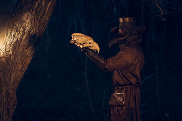 Mysterious plague doctor examines animal skull amidst dark, atmospheric woods.