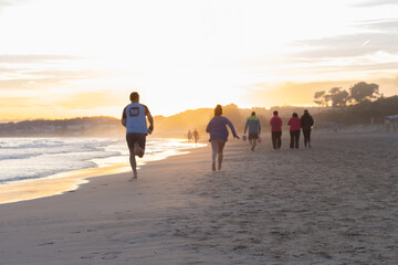 personas paseando por la playa al atardecer
