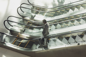 Glass-and-metal escalators moving in modern office atrium under soft light, with plant shadows