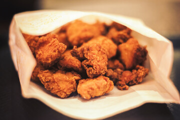 Crispy fried chicken nuggets in a paper bag, close-up shot on a white plate, India setting.