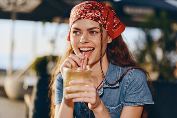 Lifestyle woman wearing modern boho-western denim street style sipping drink outdoors, smiling with natural light and warm film color tones.