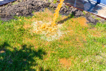 Yellow water from a pipe on the street. Selective focus.