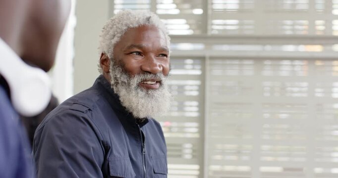African American man reacting with laughter to colleague in office meeting with headphones  and  bli
