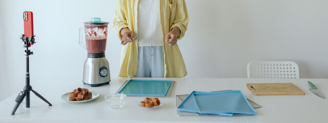 Middle aged woman preparing homemade fruit leather, slicing fresh fruit in her kitchen for healthy snack. Part of a series on organic treats and natural living. User-generated content. Live streaming