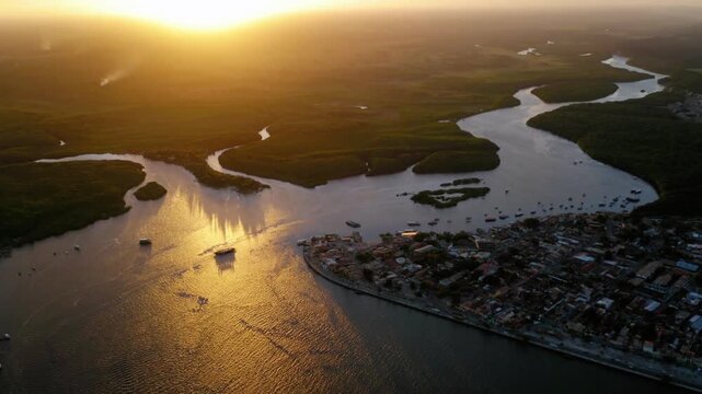 Aerial view of a city at the edge of a river during golden hour sunset