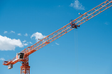 a large orange construction crane with a long boom on a blue sky background