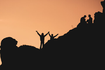 A group of people are silhouetted against a sunset