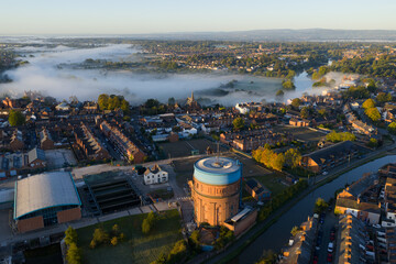 Aerial sunrise view of Chester with mist over the River Dee, terraced housing, and water tower.
