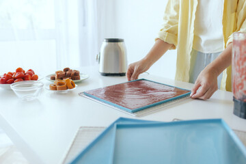 Fototapeta premium Caucasian woman preparing homemade fruit leather, slicing fresh fruit in her kitchen for a healthy snack. Part of a series on organic treats and natural living. Part of a series