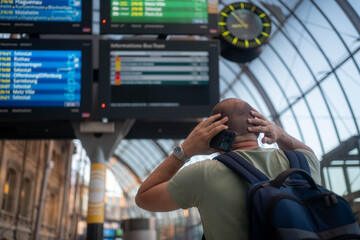 Worried man waiting for delayed airplane or train at station during travel