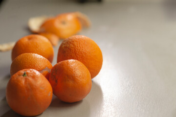 A lovely group of fresh, bright oranges is artistically displayed on a table, with their peels scattered nearby, showcasing the vibrant color and appealing natural texture of the fruits