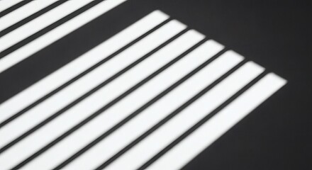 Sunlight casting a geometric pattern of diagonal shadows from window blinds onto a dark surface, offering clean copy space