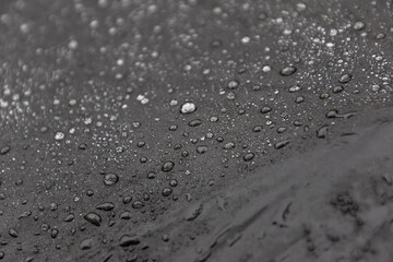Gros plan minimaliste sur un parapluie noir avec gouttes de pluie, texture épurée