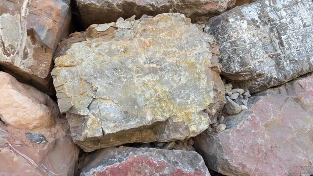 Closeup motion on yellow color square rough surface rock with jagged edges in rock wall with similar weathered erosion rocks 4k