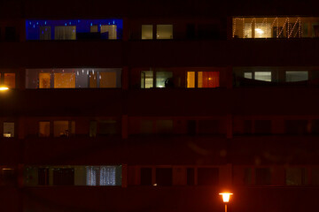 A captivating nighttime view of a grand apartment building features brightly lit windows with...