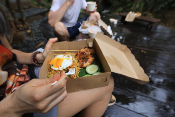 Person is eating food from a brown box