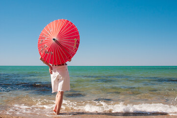 Girl with red umbrella on a sea shore