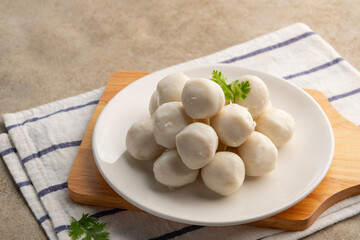 Uncooked Thai Pork meatballs on white plate.