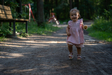 joyful toddler in pink dress exploring a sunlit forest path with playful stride, surrounded by lush greenery, wooden bench, and playground swing in the background, serene, natural, shadows, peaceful