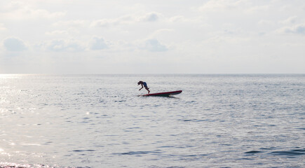 Young boy dives into the sea from the puddle board. Fun