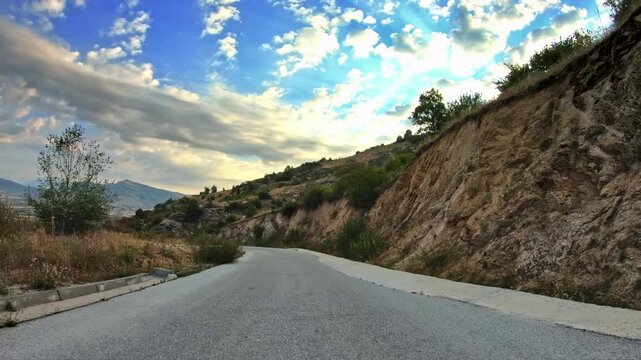 POV driving across beautiful nature, hilly terrain, clouds, summer day
