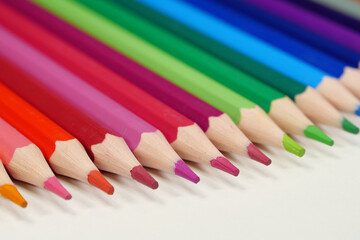 New wooden colored pencils of rainbow colors, perfectly sharpened, lie on table