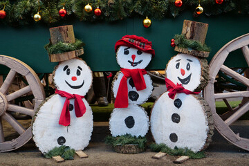 Three cheerful wooden snowmen are smiling