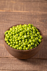 Fresh green peas and pods in a bowl on wooden table. Vegetable healthy food.  