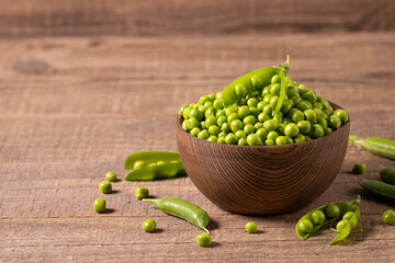 Fresh green peas and pods in a bowl on wooden table. Vegetable healthy food.  