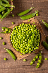 Fresh green peas and pods in a bowl on wooden table. Vegetable healthy food.  