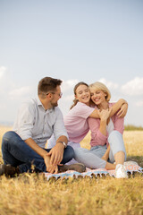 Fototapeta premium Family enjoys a cheerful picnic in a sunny field together during a warm afternoon