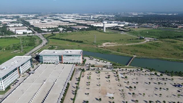 Corporate buildings with flat roofs, lake, bridge, vacant land, and distant warehouses highlighting commercial real estate, stormwater planning, and environmental integration near DFW airport, TX